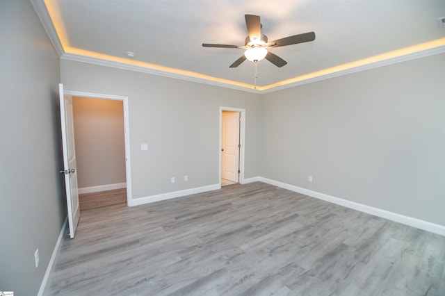 unfurnished room with a tray ceiling, ceiling fan, and baseboards