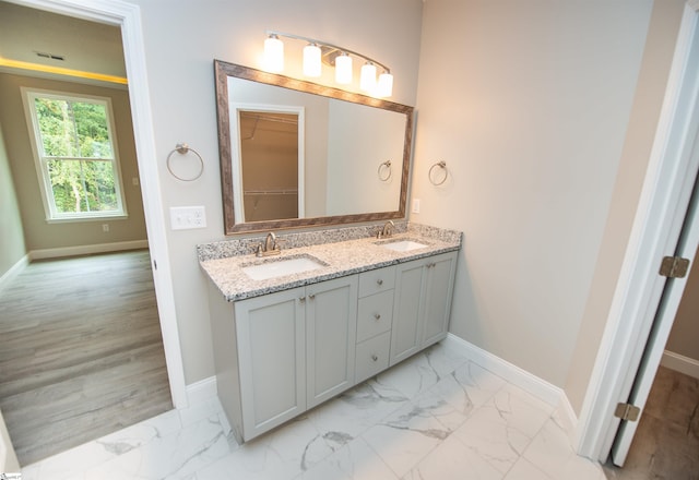 full bath featuring marble finish floors, baseboards, and double vanity