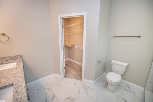 full bath featuring marble look tiles, toilet, baseboards, and a spacious closet