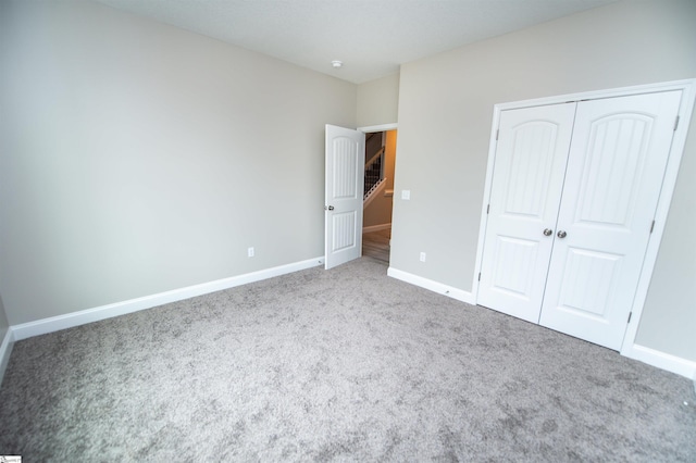 unfurnished bedroom with carpet, baseboards, and a closet