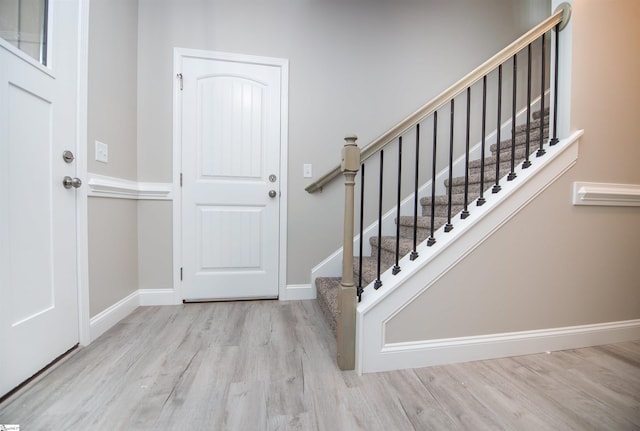 entrance foyer with wood finished floors, baseboards, and stairway