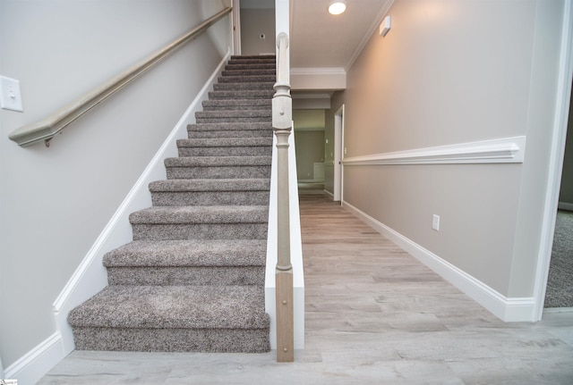 stairway with baseboards, wood finished floors, ornamental molding, and recessed lighting