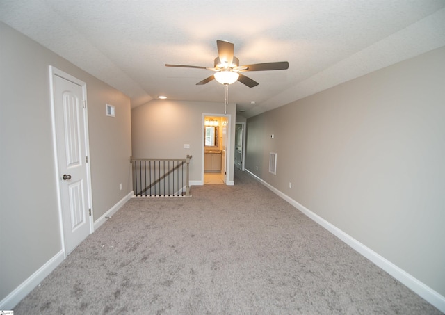empty room with carpet floors, ceiling fan, baseboards, and vaulted ceiling