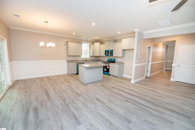 kitchen featuring stainless steel appliances, crown molding, ceiling fan, a kitchen island, and a chandelier
