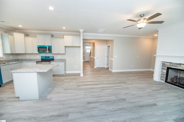 kitchen featuring appliances with stainless steel finishes, a ceiling fan, crown molding, a fireplace, and recessed lighting