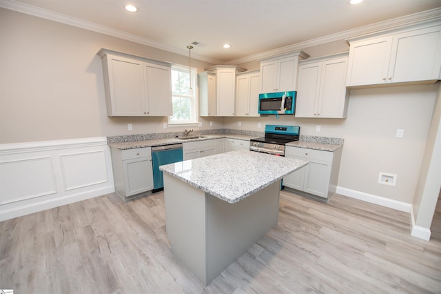 kitchen featuring stainless steel appliances, a sink, crown molding, a center island, and light wood finished floors