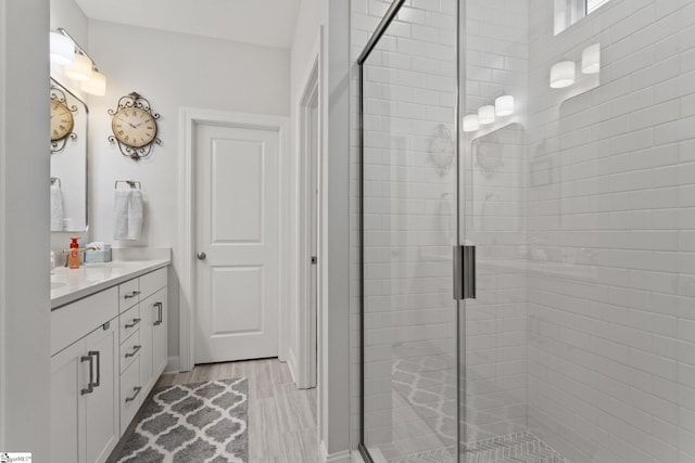 bathroom with walk in shower, vanity, and hardwood / wood-style floors