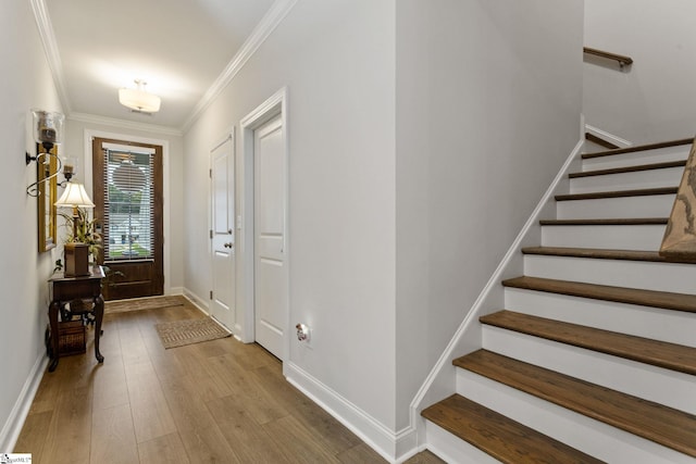 foyer entrance with light hardwood / wood-style floors and ornamental molding