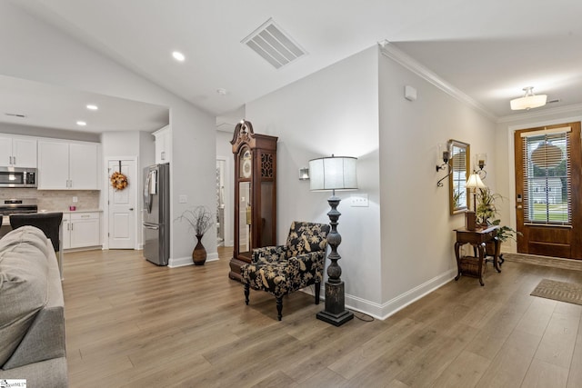 foyer featuring vaulted ceiling, light hardwood / wood-style flooring, and ornamental molding