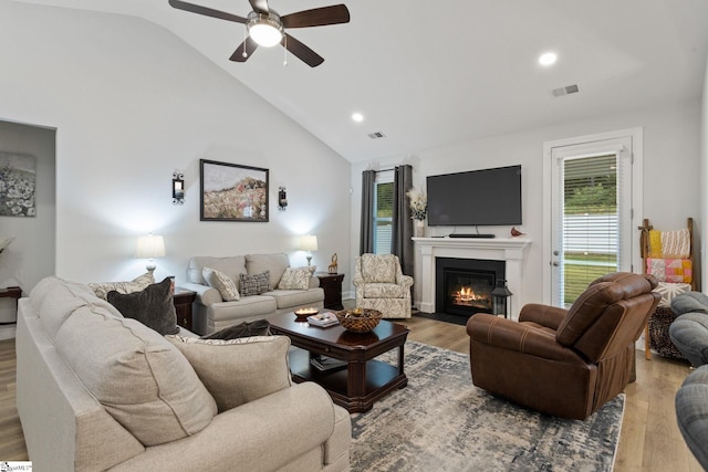 living room with light wood-type flooring, vaulted ceiling, and ceiling fan