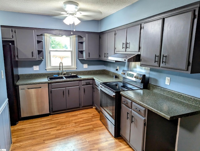 kitchen with ceiling fan, appliances with stainless steel finishes, a textured ceiling, light wood-type flooring, and sink