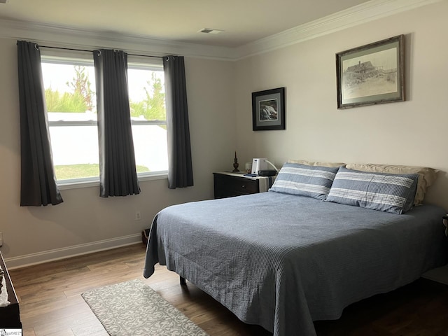 bedroom with multiple windows, hardwood / wood-style flooring, and crown molding