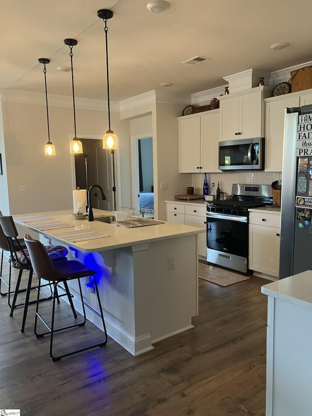 kitchen with dark hardwood / wood-style floors, an island with sink, white cabinets, hanging light fixtures, and stainless steel appliances