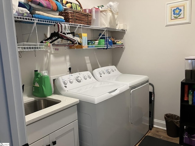 washroom featuring wood-type flooring, sink, independent washer and dryer, and cabinets