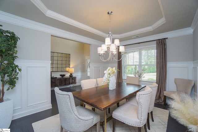 dining area featuring a raised ceiling, ornamental molding, an inviting chandelier, and dark hardwood / wood-style flooring