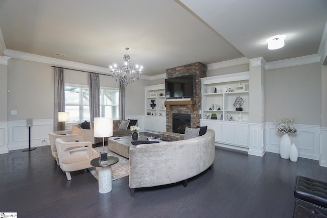 living room with a stone fireplace, ornamental molding, dark wood-type flooring, and a chandelier