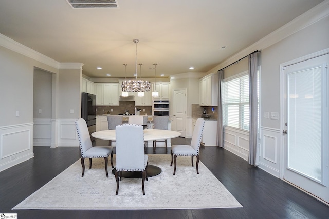 dining area with ornamental molding, an inviting chandelier, and dark hardwood / wood-style flooring