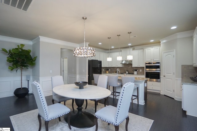 dining room featuring ornamental molding, dark hardwood / wood-style floors, a chandelier, and sink