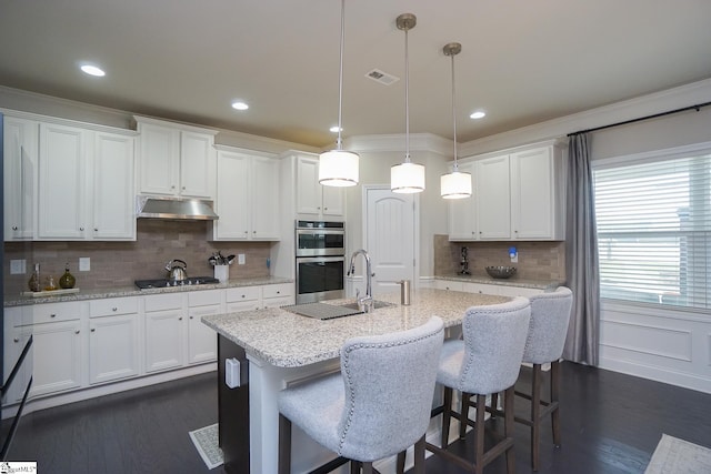 kitchen featuring stainless steel double oven, hanging light fixtures, and white cabinetry