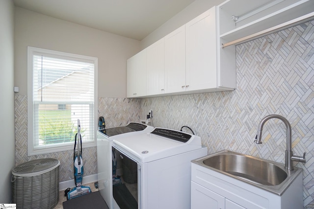 washroom featuring a healthy amount of sunlight, sink, independent washer and dryer, and cabinets