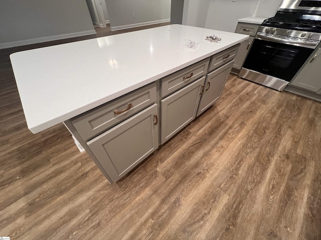 kitchen with gray cabinets, stainless steel gas stove, and dark wood finished floors