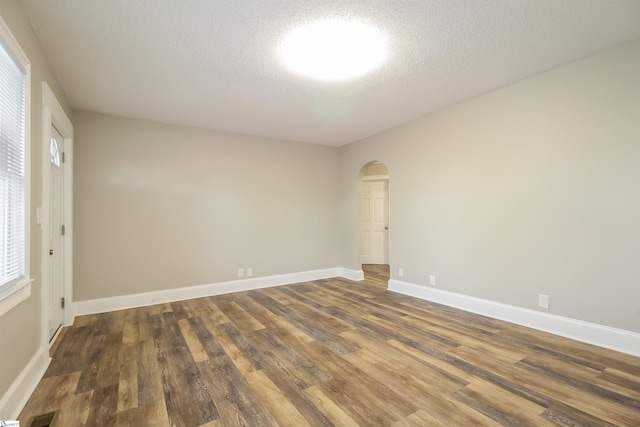 spare room featuring a textured ceiling and dark wood-type flooring