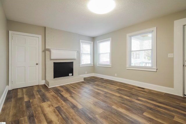 unfurnished living room with a fireplace, plenty of natural light, and dark wood-type flooring