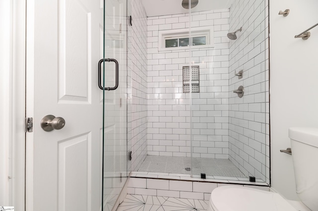 bathroom with a shower with shower door and toilet