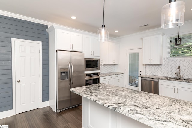 kitchen with sink, white cabinetry, decorative backsplash, stainless steel appliances, and decorative light fixtures