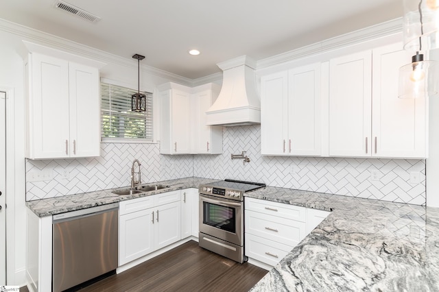 kitchen featuring sink, white cabinets, custom exhaust hood, stainless steel appliances, and decorative light fixtures