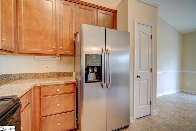 kitchen featuring black range oven, stainless steel fridge, and light tile patterned floors