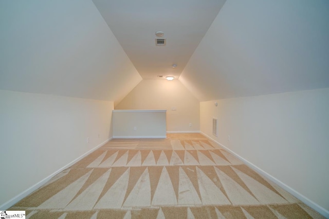 bonus room with light carpet and vaulted ceiling