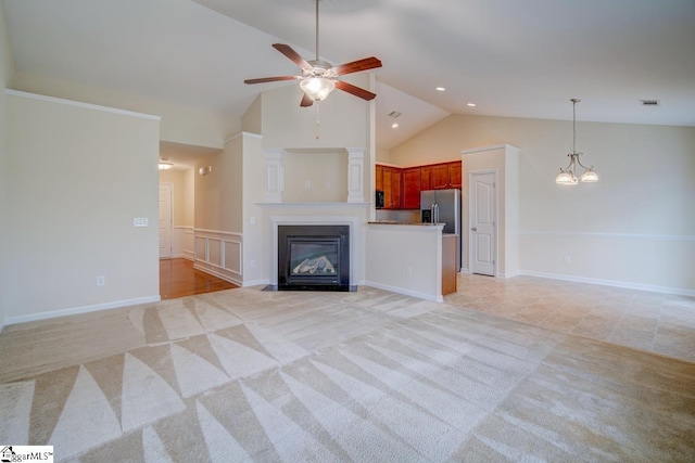 unfurnished living room with ceiling fan with notable chandelier, vaulted ceiling, and light colored carpet