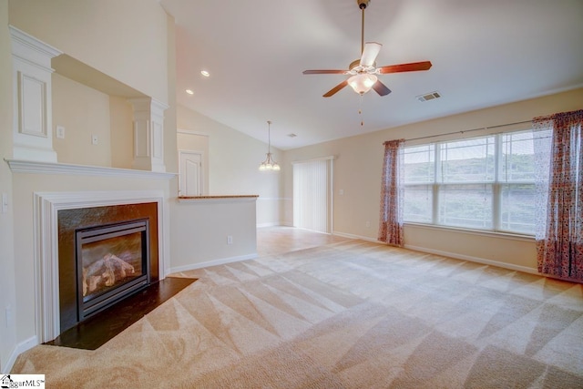 unfurnished living room with carpet flooring, ceiling fan with notable chandelier, a premium fireplace, and vaulted ceiling