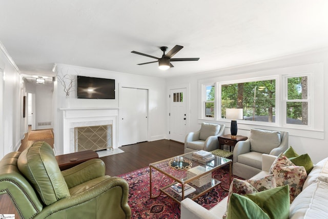 living room featuring ceiling fan, dark hardwood / wood-style floors, a fireplace, and crown molding