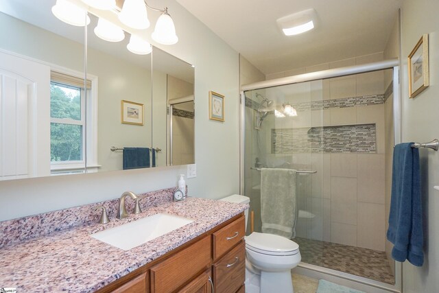 bathroom featuring vanity, a shower with shower door, and toilet