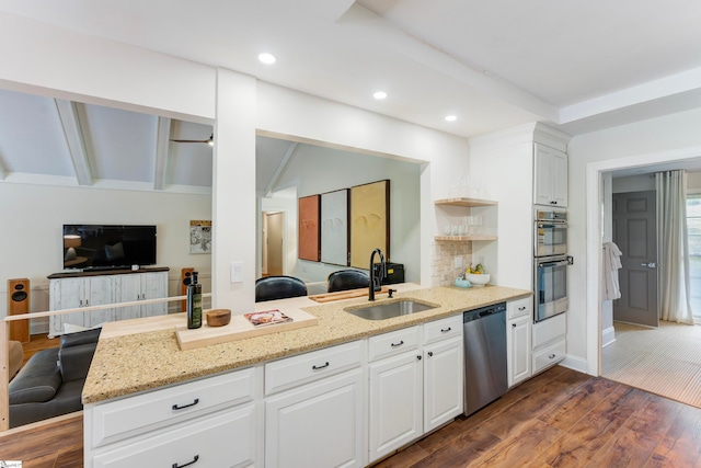 kitchen featuring white cabinets, sink, kitchen peninsula, dark wood-type flooring, and stainless steel appliances