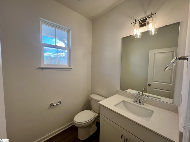 bathroom with toilet, vanity, and wood-type flooring