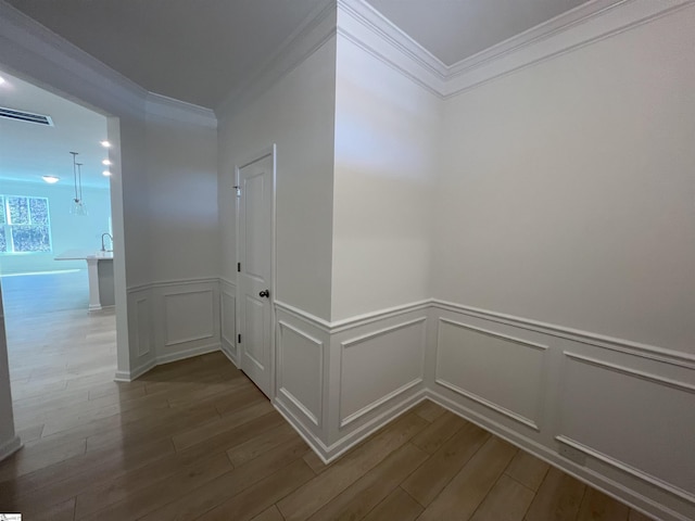 hall with light hardwood / wood-style flooring and ornamental molding