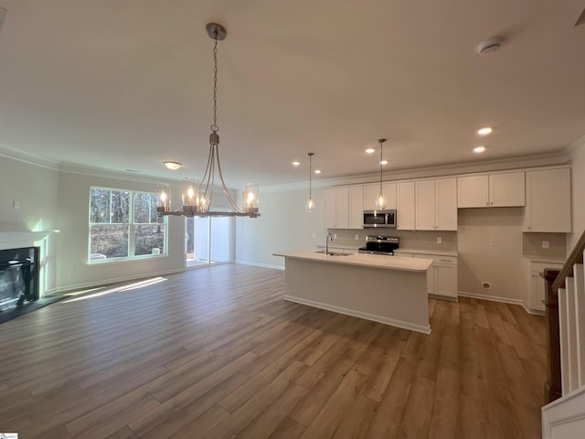 kitchen with stainless steel appliances, sink, white cabinets, and decorative light fixtures