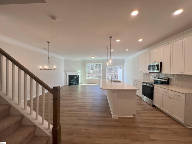 kitchen featuring white cabinets, backsplash, an island with sink, and stainless steel appliances