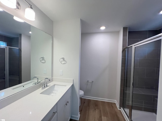 bathroom with hardwood / wood-style flooring, toilet, vanity, and a shower with shower door