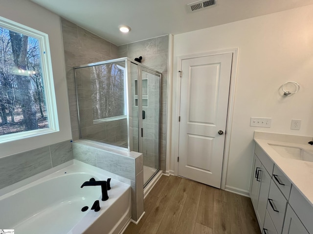 bathroom featuring shower with separate bathtub, hardwood / wood-style floors, and vanity