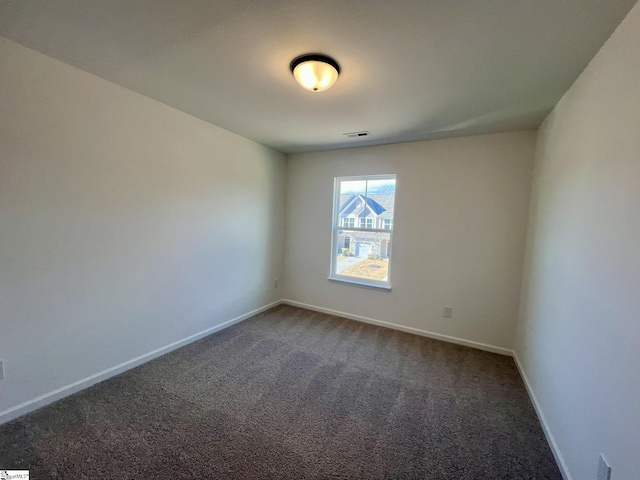 unfurnished room featuring dark carpet