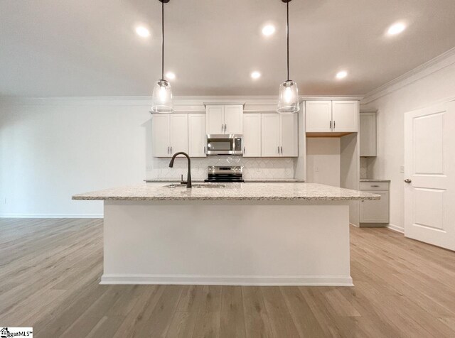 214 Brochaill Ct, Piedmont, SC 29673 - kitchen with a kitchen island with sink, light stone counters, pendant lighting, and appliances with stainless steel finishes