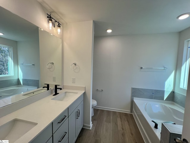 bathroom with toilet, vanity, a washtub, and hardwood / wood-style flooring