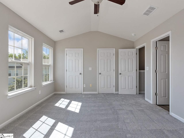 unfurnished bedroom with lofted ceiling, ceiling fan, light colored carpet, and multiple closets