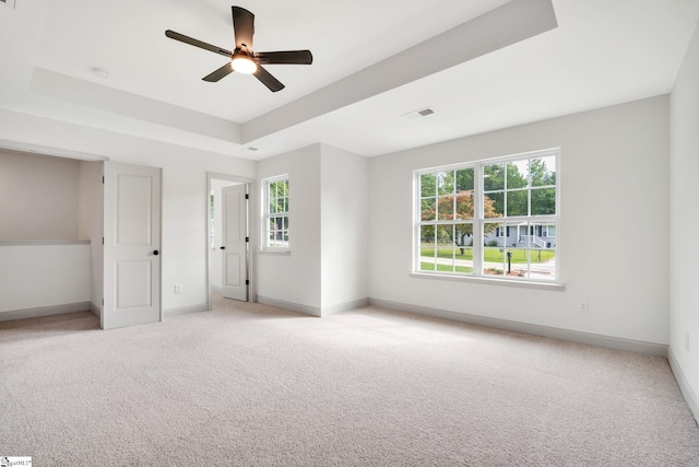 unfurnished bedroom with a tray ceiling, ceiling fan, and light colored carpet