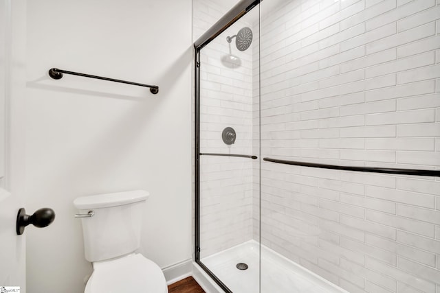 bathroom featuring toilet and a shower with door