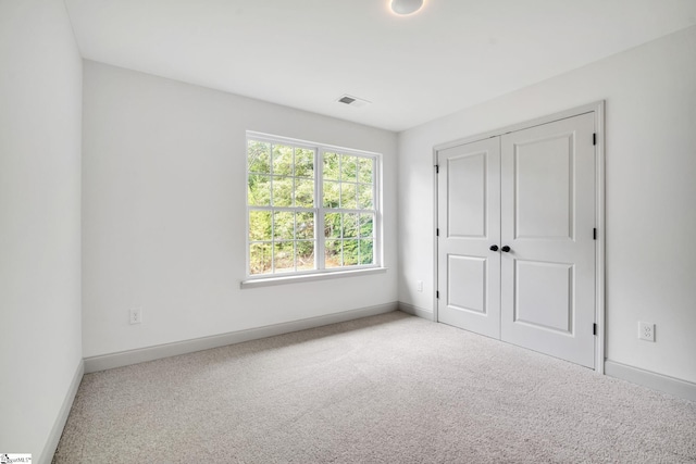 unfurnished bedroom with light carpet and a closet